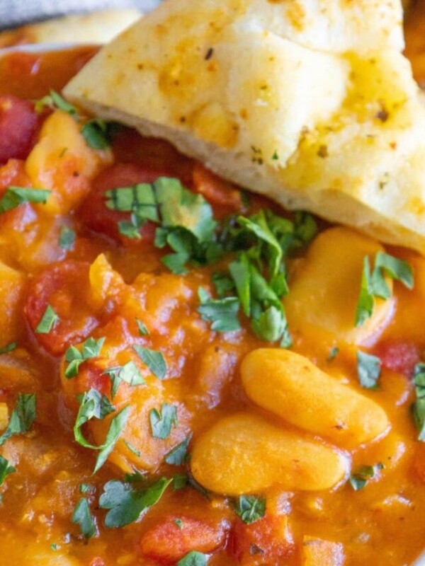 baked greek beans in a tomato sauce with chopped herbs and giant white beans
