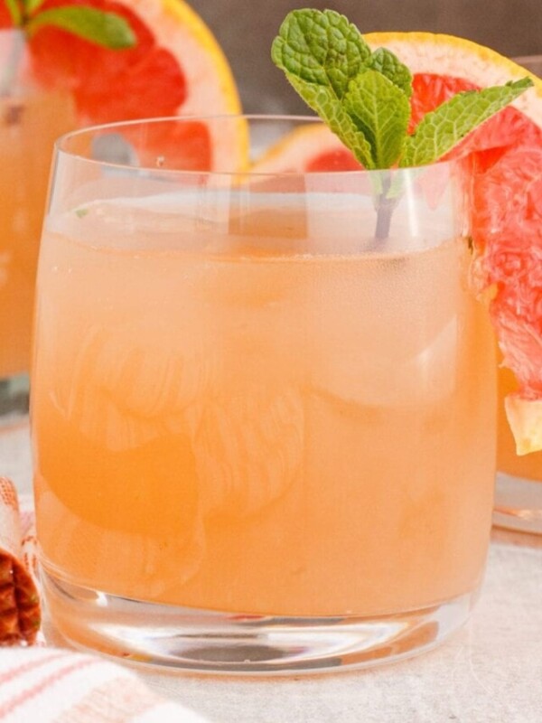 pink mojito in a short glass with a slice of grapefruit and a sprig of mint on the rim