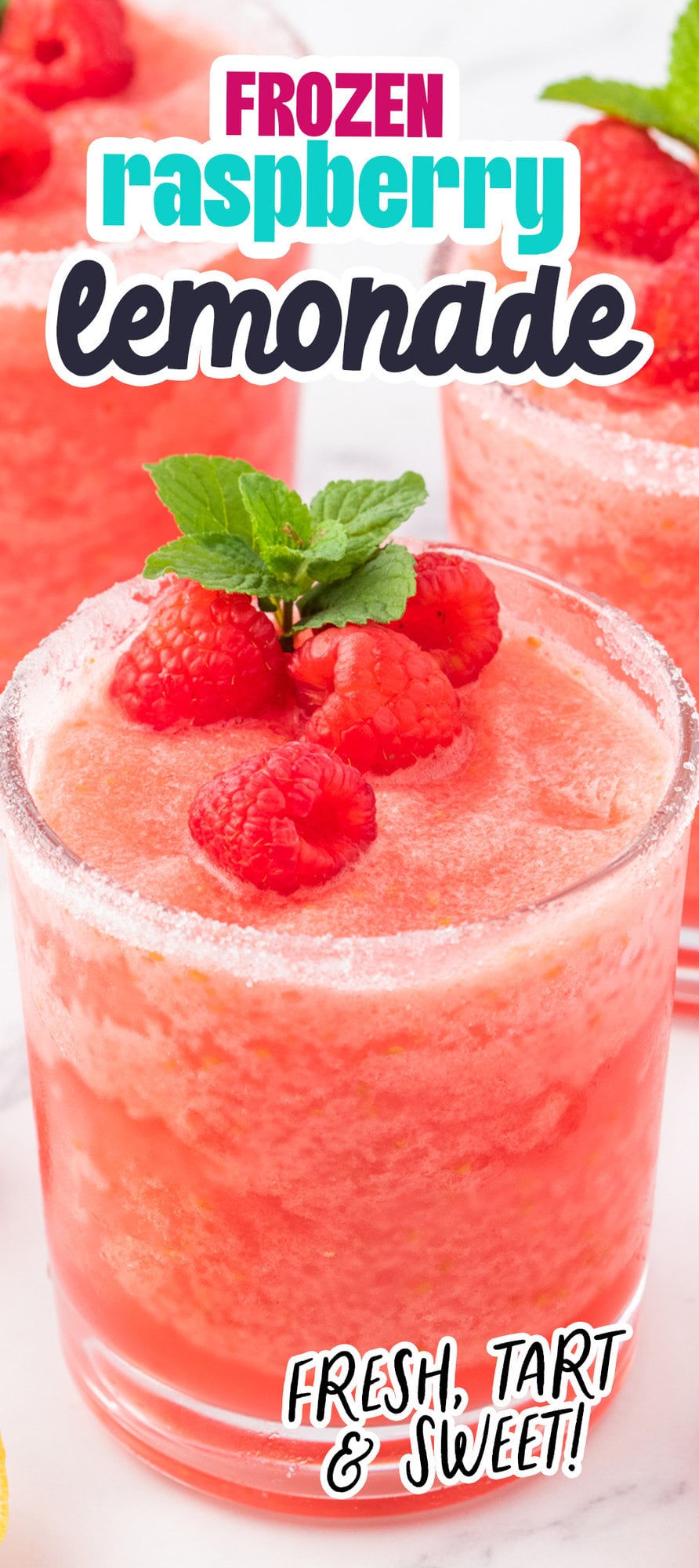 frozen pink lemonade in a sugar rimmed glass with raspberries and a sprig of mint on top