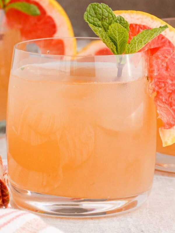 pink mojito in a short glass with a slice of grapefruit and a sprig of mint on the rim