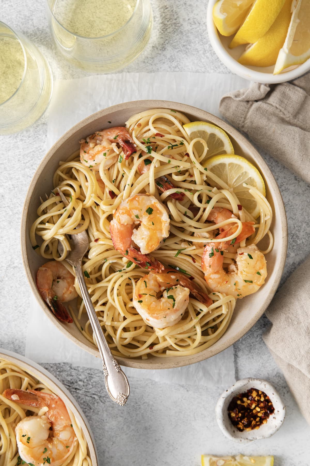 shrimp pasta with linguine, red pepper flakes, herbs, and lemon slices in a bowl