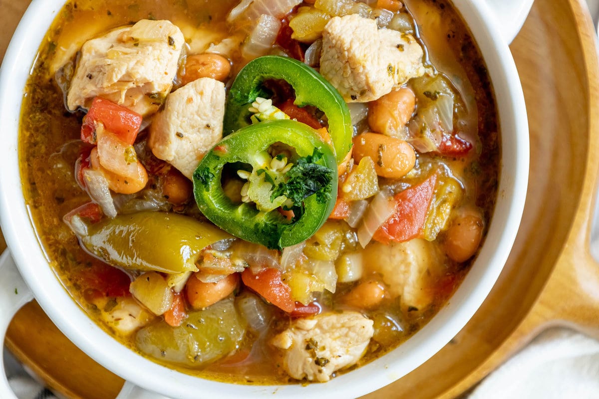 chicken stew with diced chicken breasts, tomatillos, onions, pinto beans, diced tomatoes, and sliced jalapeños on top
