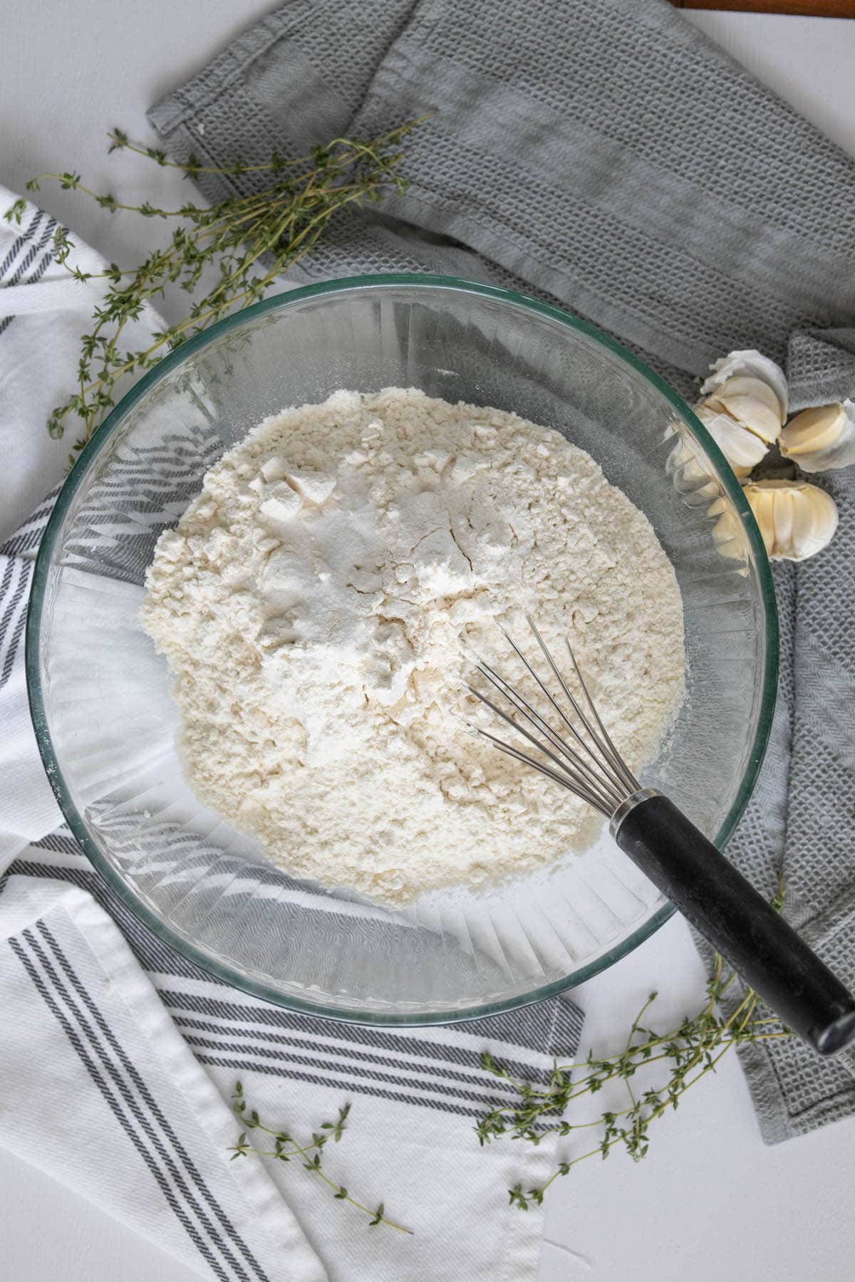 A bowl of flour and a whisk on a table used in making easy overnight focaccia.