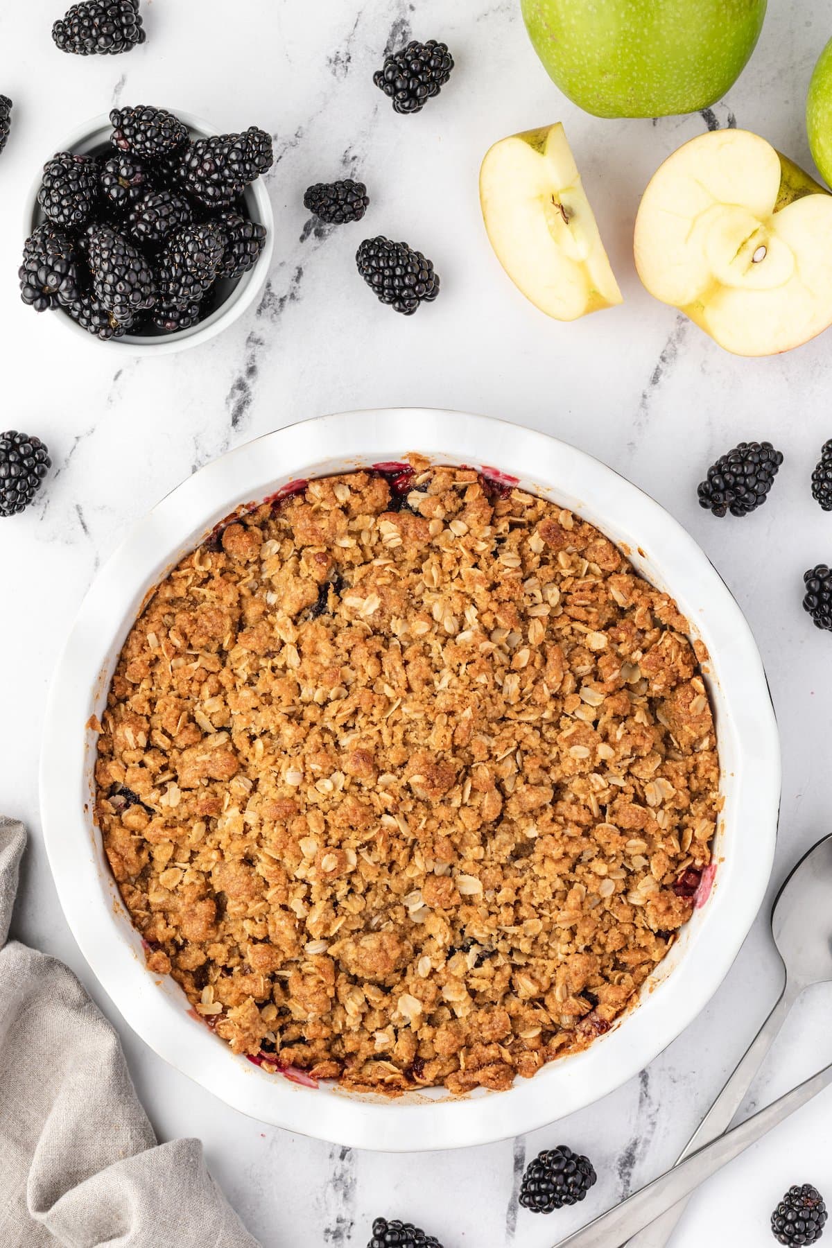 Blackberry crisp with apples and berries in a white dish.