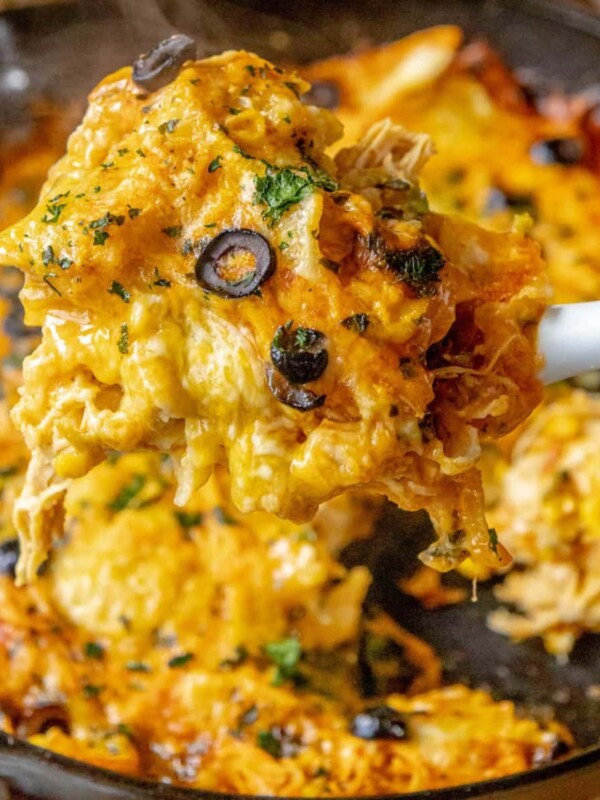 cheesy chicken enchilada skillet on a spatula over a cast iron pan