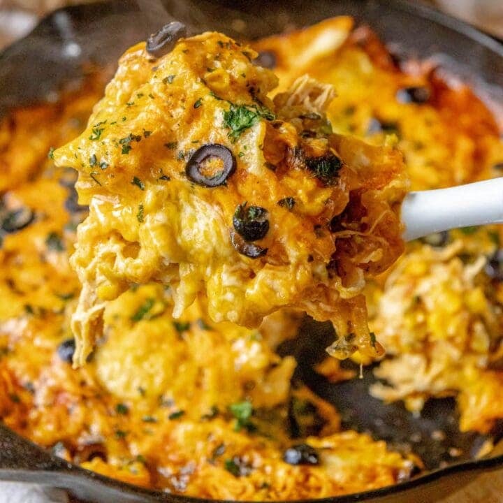 cheesy chicken enchilada skillet on a spatula over a cast iron pan