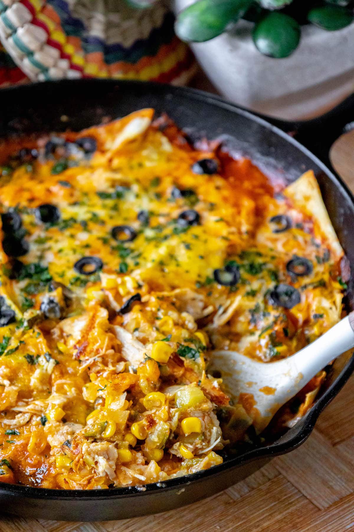cheesy chicken enchilada skillet on a spatula in a cast iron pan