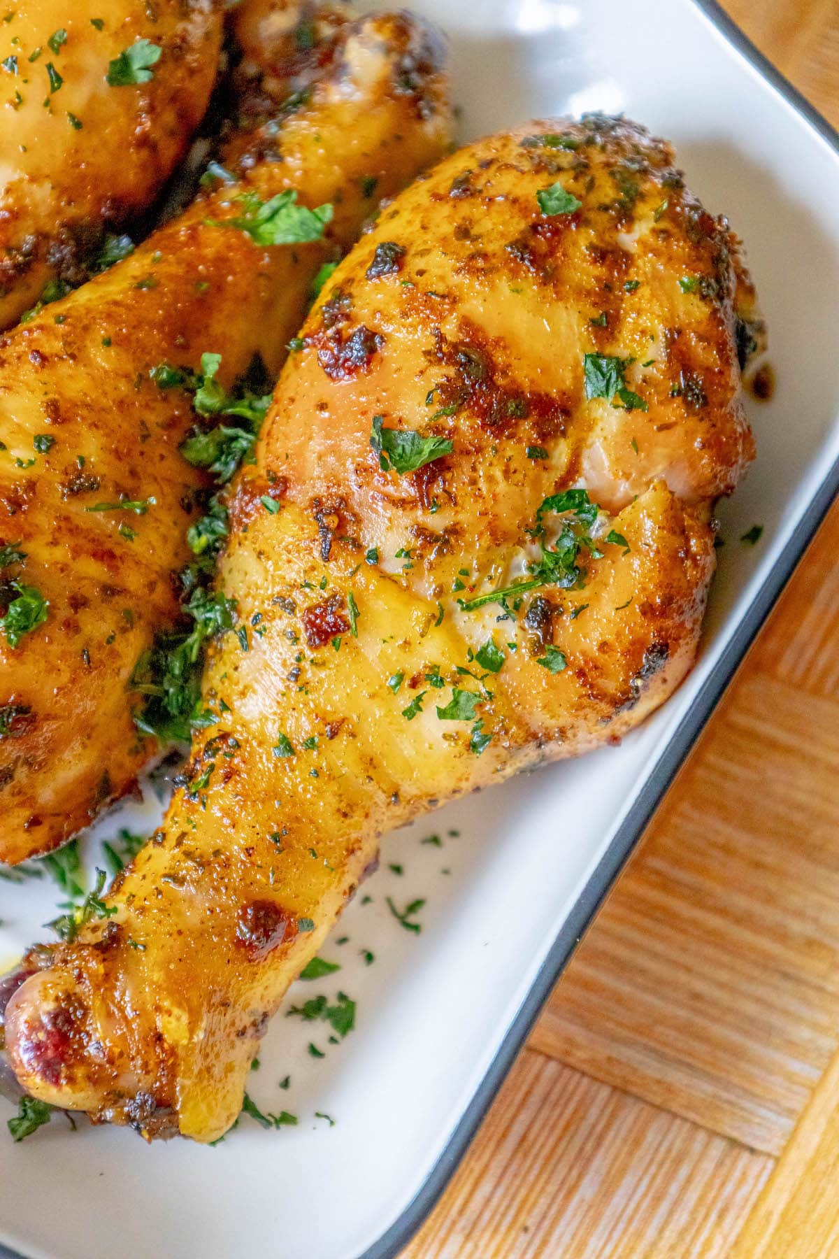 chicken confit drumsticks topped with parsley in a white dish