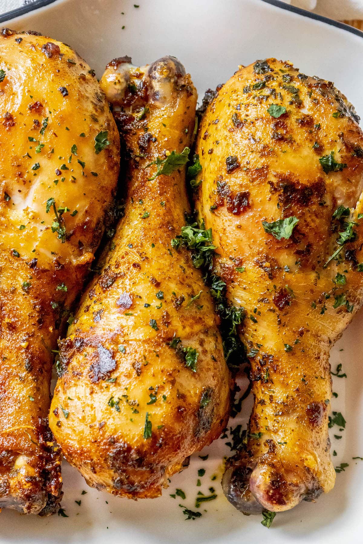 chicken confit drumsticks topped with parsley in a white dish