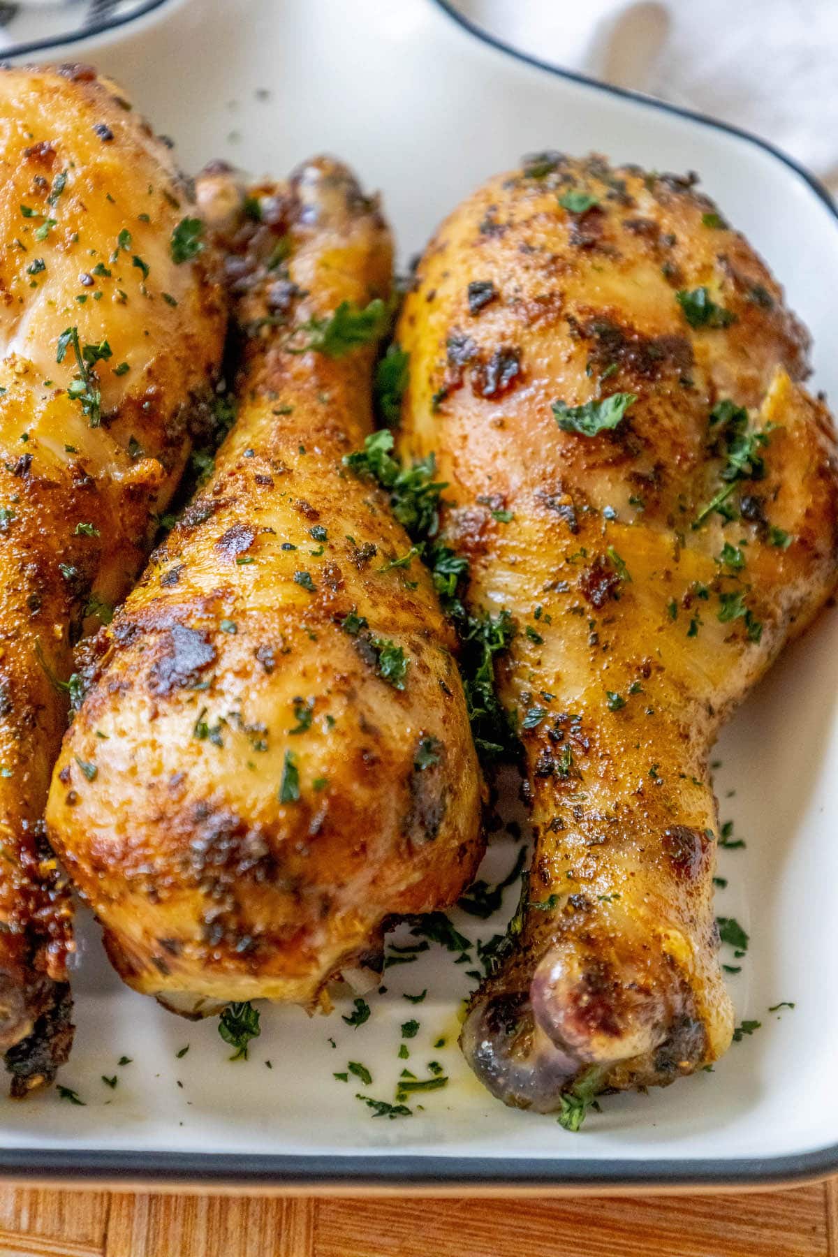 chicken confit drumsticks topped with parsley in a white dish