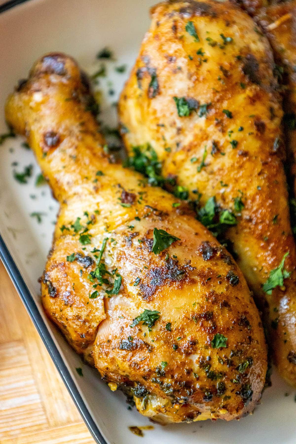 chicken confit drumsticks topped with parsley in a white dish