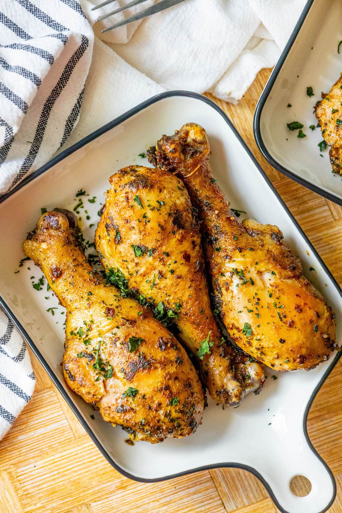 chicken confit drumsticks topped with parsley in a white dish