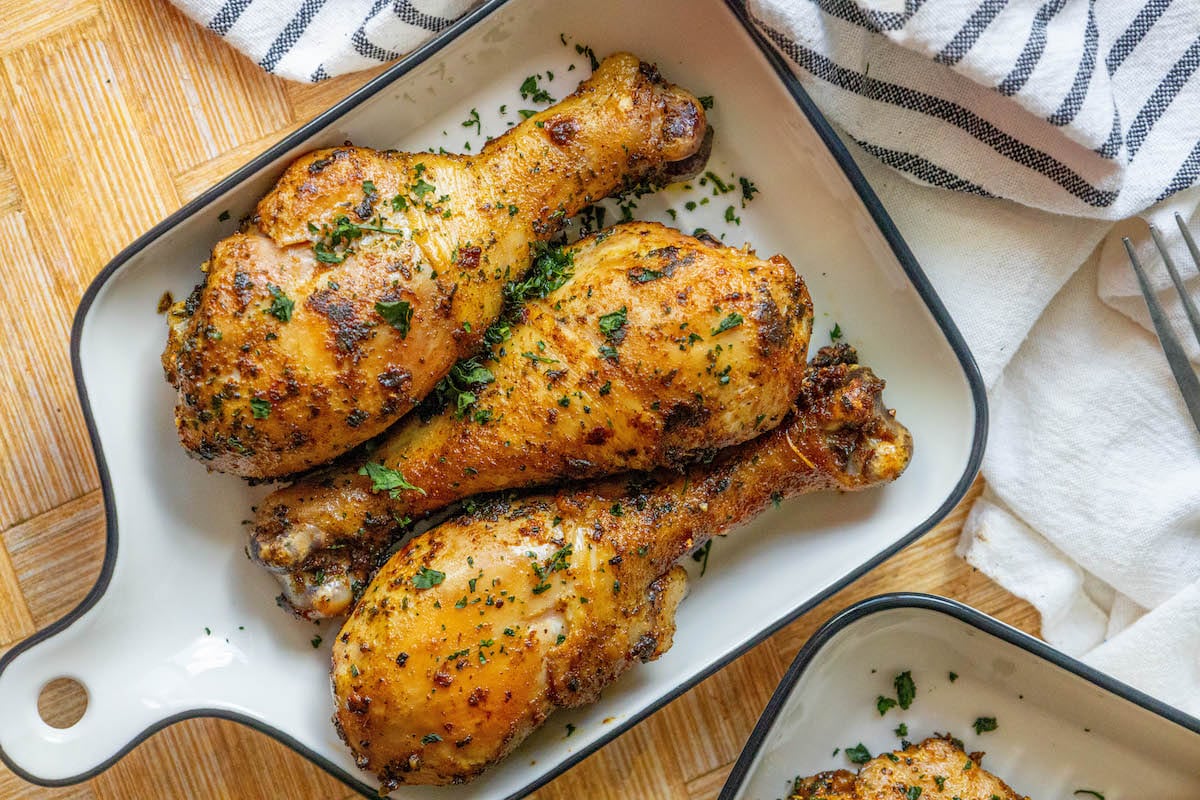 chicken confit drumsticks topped with parsley in a white dish