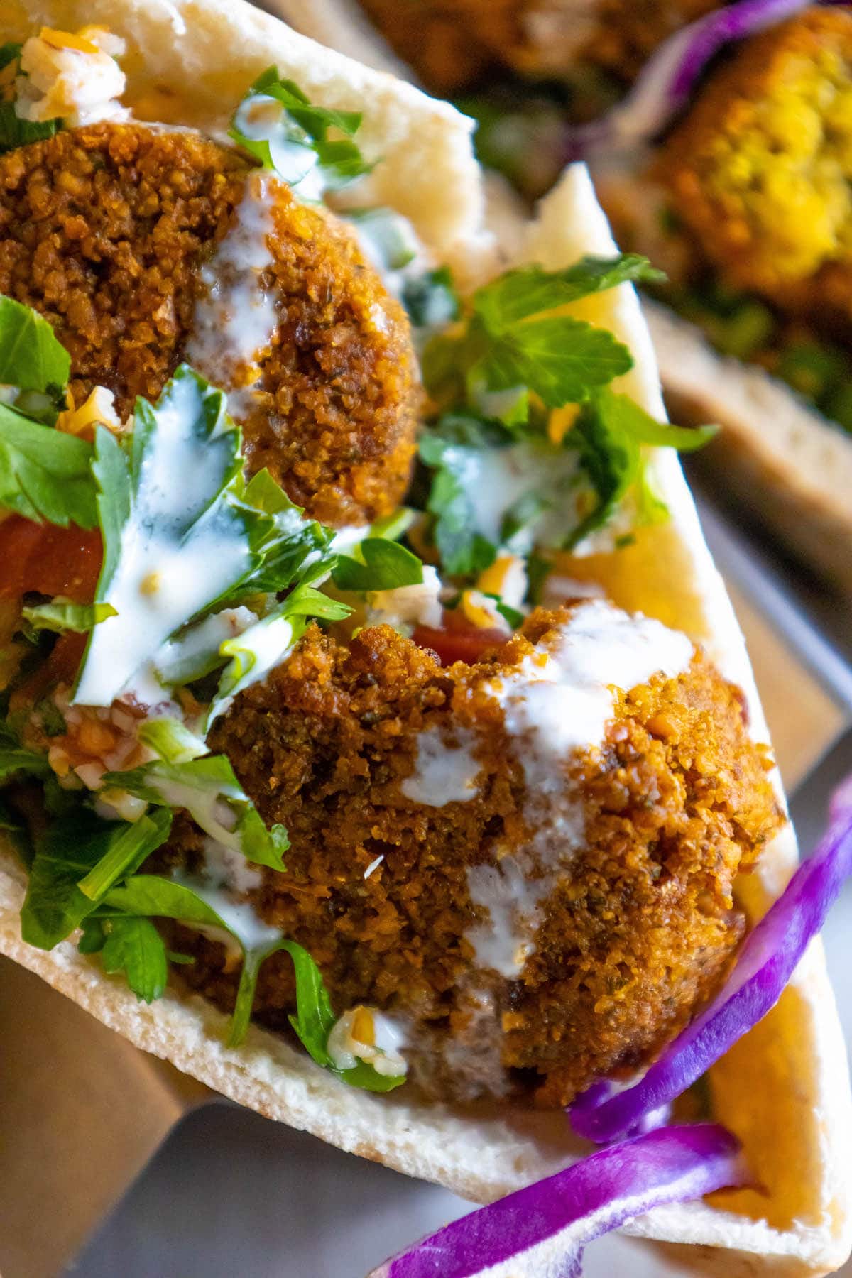 pita stuffed with falafel balls, cabbage, and salad with tahini sauce ladled on top