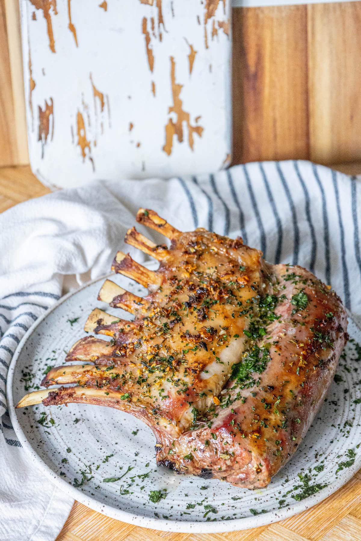 roasted rack of lamb with garlic and herb crust on a white speckled plate on a table