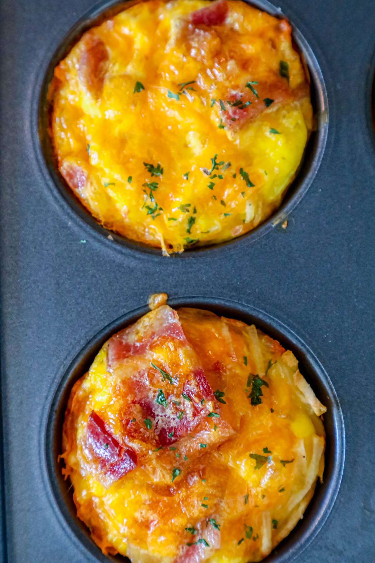 egg cups with bacon and hashbrown stacked on top of each other on a black plate