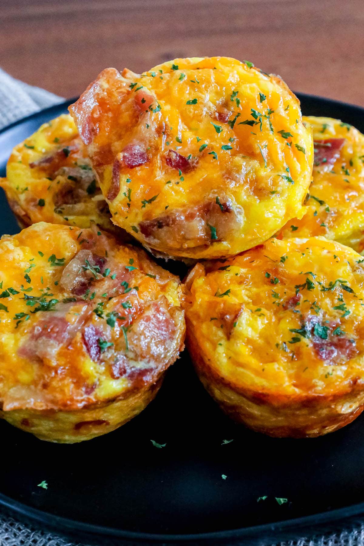 egg cups with bacon and hashbrown stacked on top of each other on a black plate