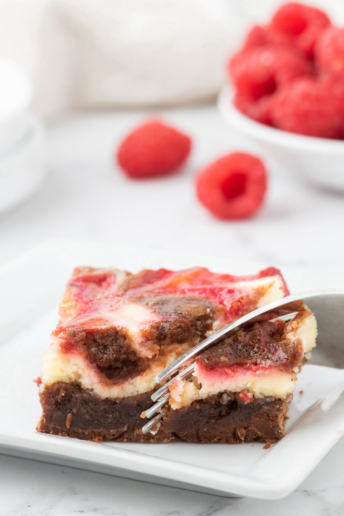 cheesecake marbled brownie bar with raspberry sauce on top