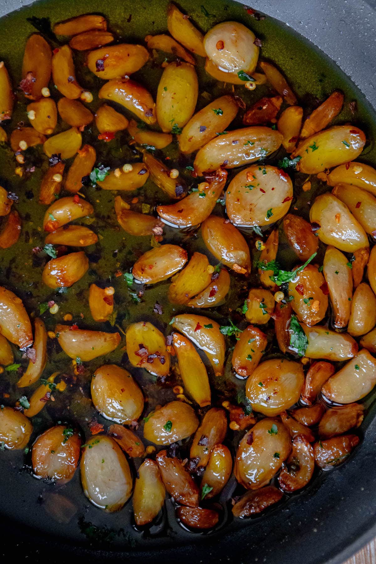 A frying pan with a delicious Garlic Confit recipe cooking.