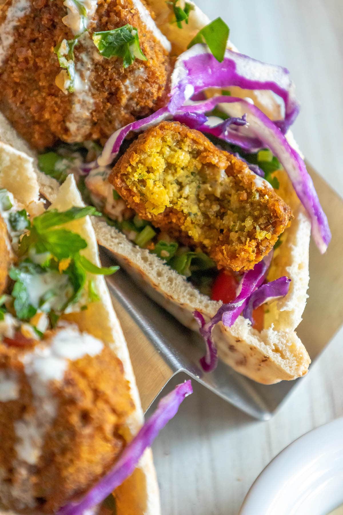 pita stuffed with falafel balls, cabbage, and salad with tahini sauce ladled on top