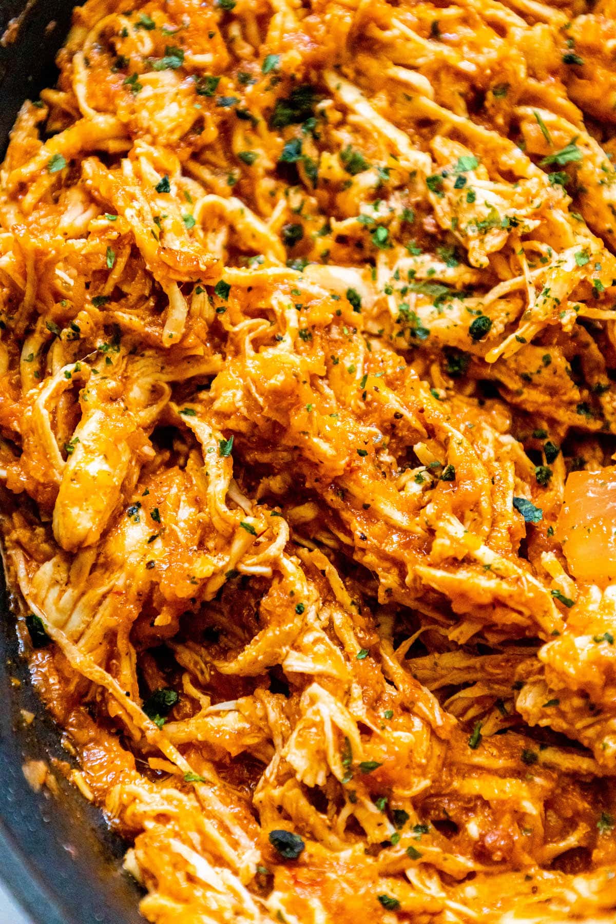 shredded chicken tinga in a pan with chopped cilantro on top