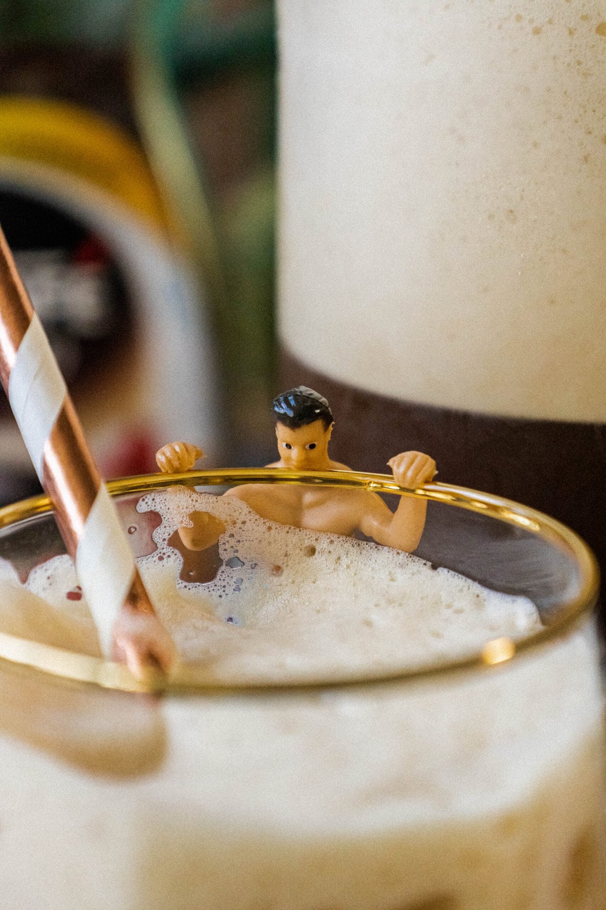 plastic wine charm shaped like a man in a swimsuit on a glass of frappé coffee with a straw