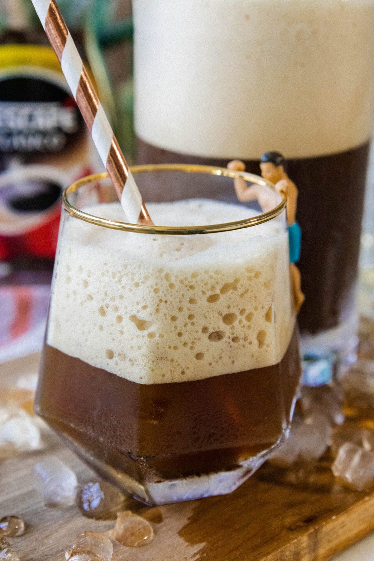 whipped Greek frappé coffee in a glass with ice and foam and a paper straw on a table