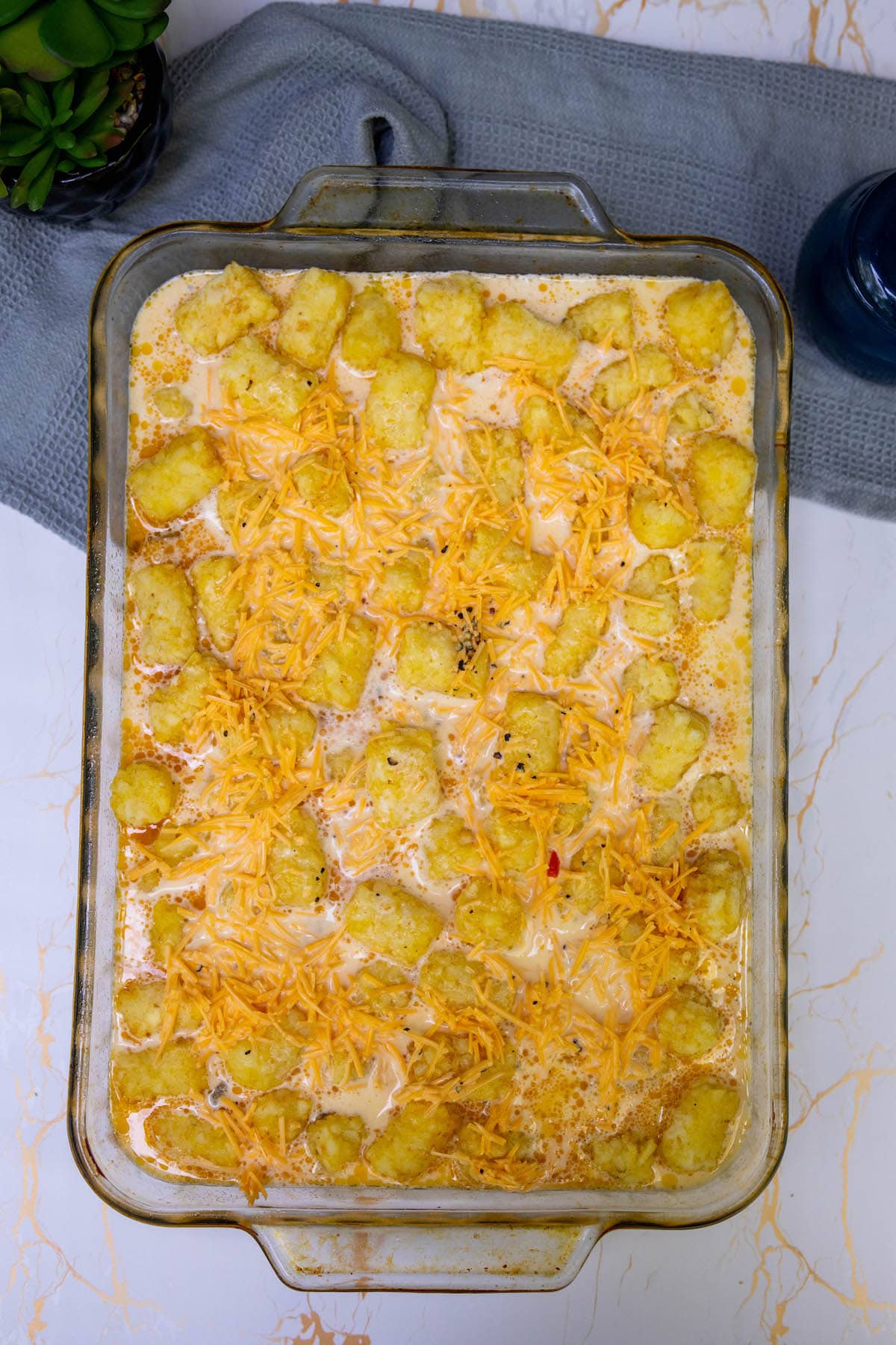 egg and milk topping over tater tots and vegetables in a baking dish