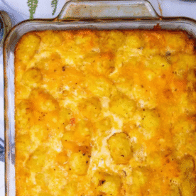 A glass baking dish filled with golden-brown tater tot breakfast casserole topped with melted cheese.