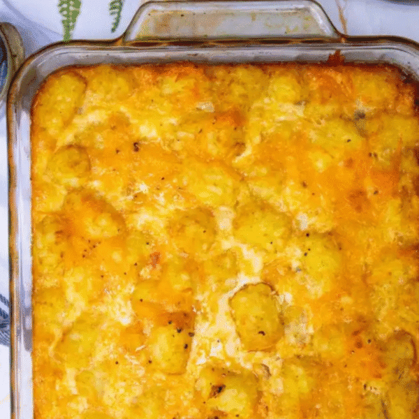 A glass baking dish filled with golden-brown tater tot breakfast casserole topped with melted cheese.