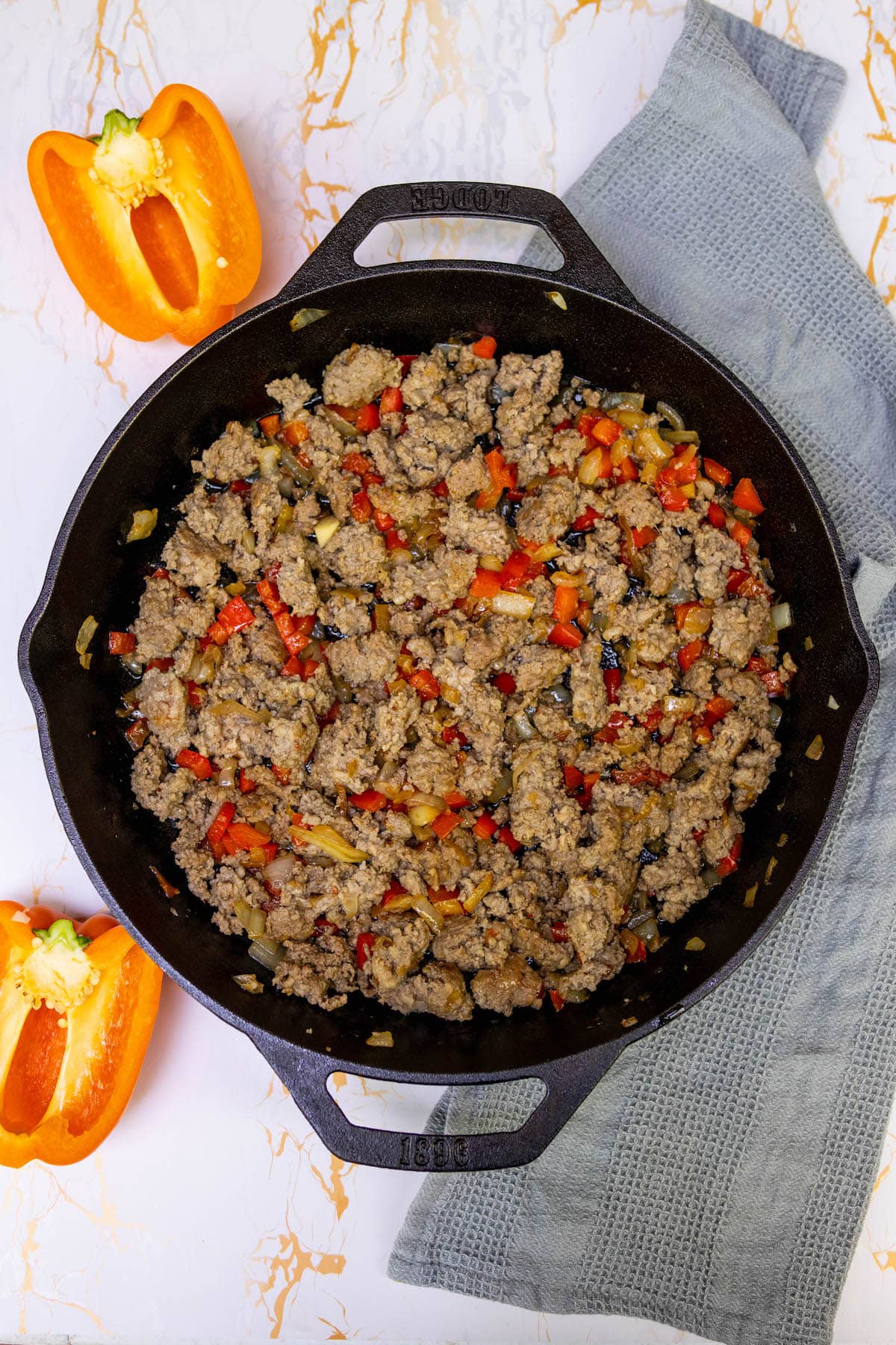 vegetables and sausage being browned in a pan