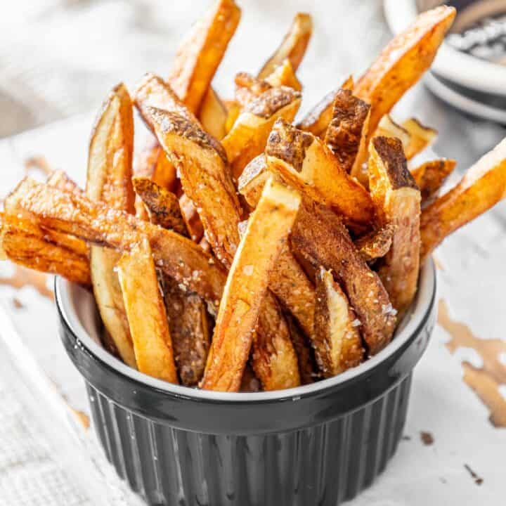 Crispy sweet potato fries in a black bowl.