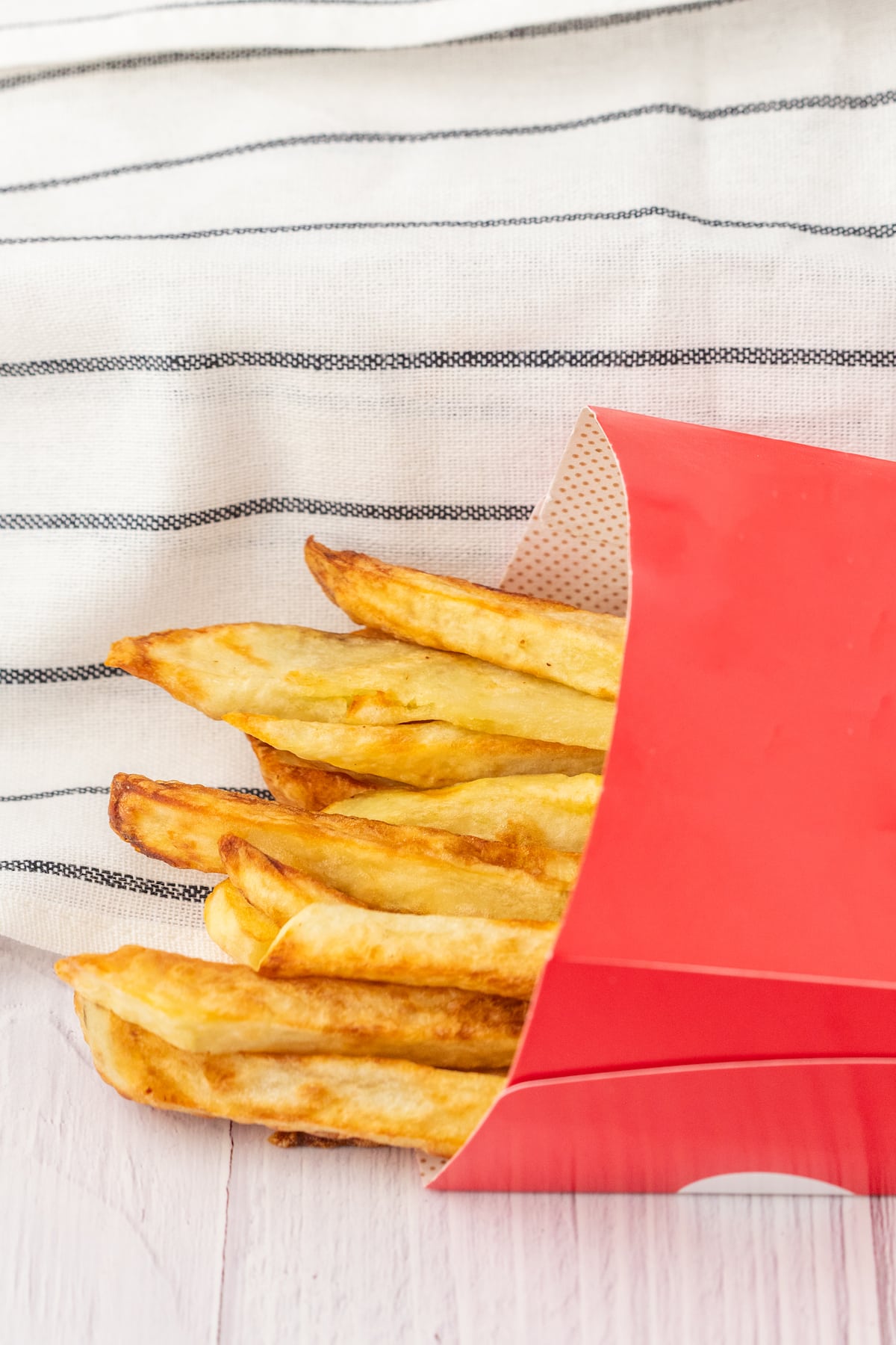 crispy fried french fries in a red paper sleeve