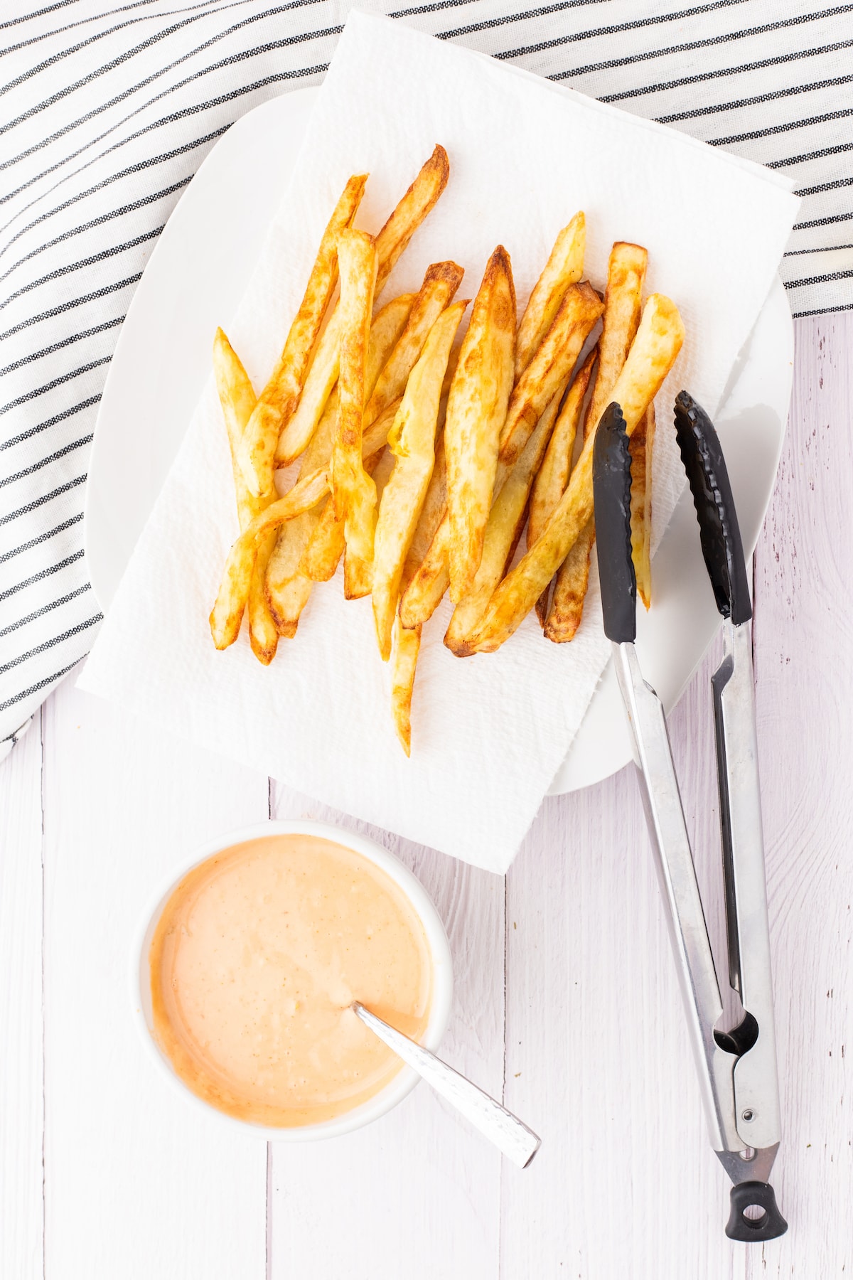 french fries on a plate next to fry sauce in a white cup 