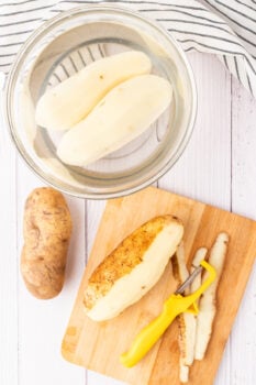 potatoes on a cutting board being peeled