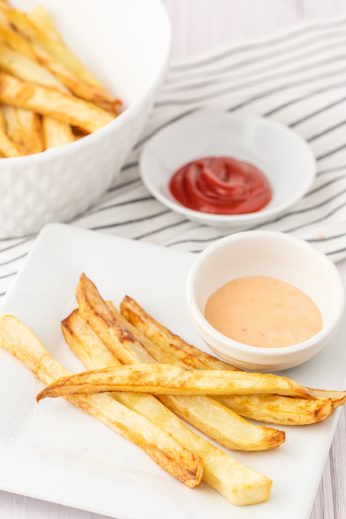 fries on a white plate next to a cup of fry sauce