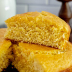 a wedge of honey butter cornbread sliced and placed on top of the loaf of cornbread on a table