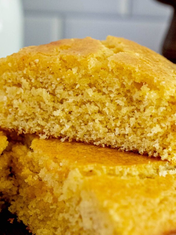 a wedge of honey butter cornbread sliced and placed on top of the loaf of cornbread on a table