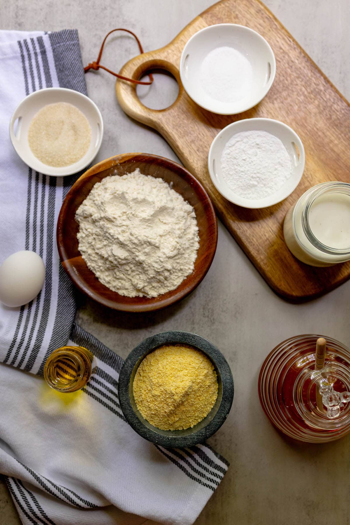 flour, sugar, corn, eggs, milk, and other cornbread ingredients on a table