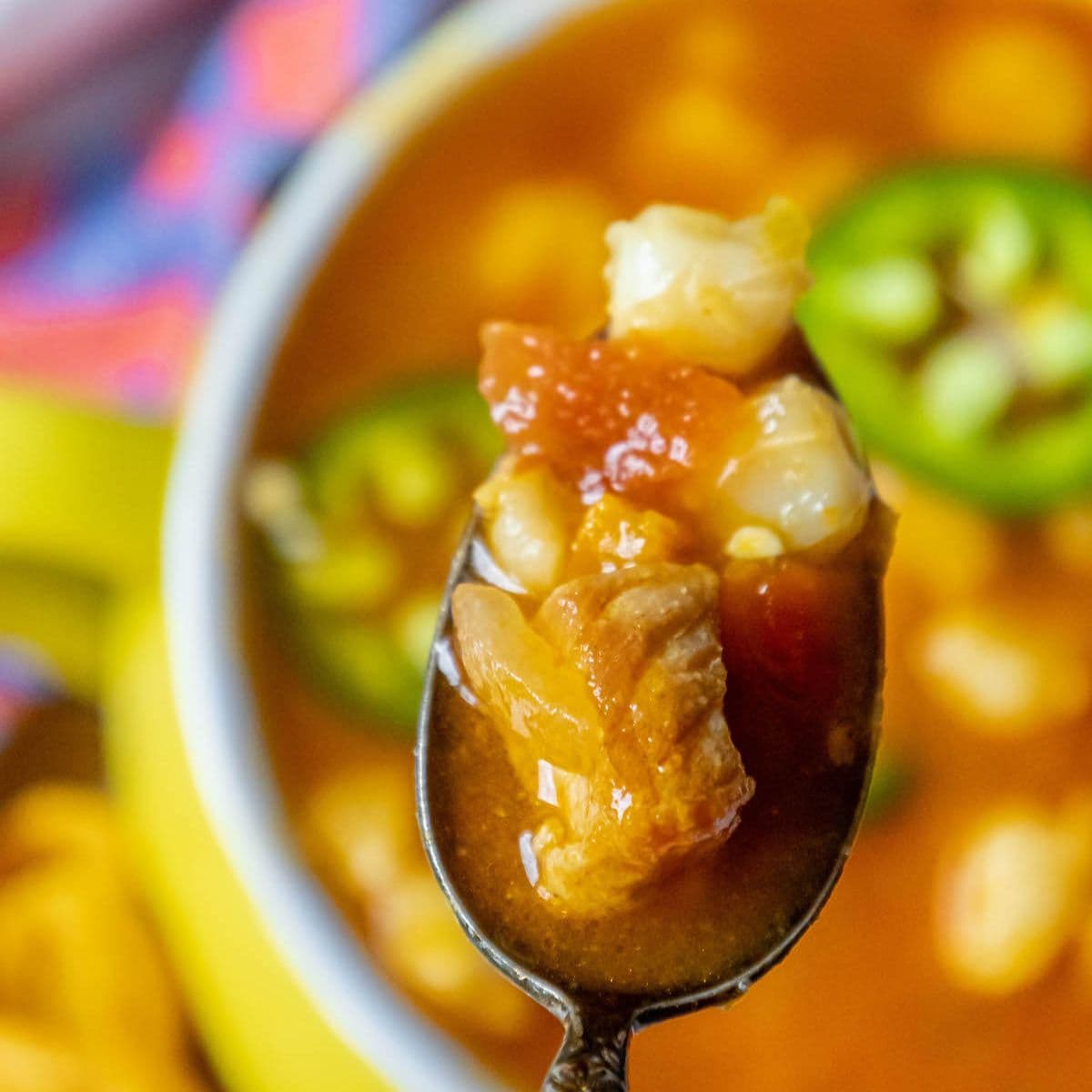 A vibrant bowl of Red Pozole, a traditional Mexican stew with tender pork and hominy in a rich red chili broth.