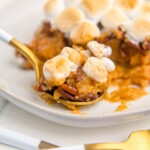 Sweet potato casserole topped with marshmallows and pecans on a plate.