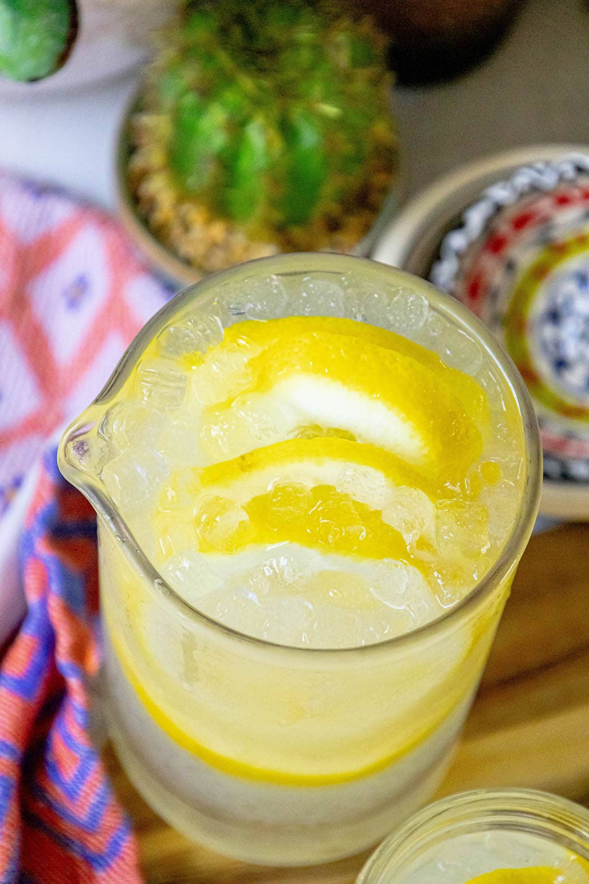 lemonade in a glass jar with a slice of lemon on the side and pebble ice in the glass