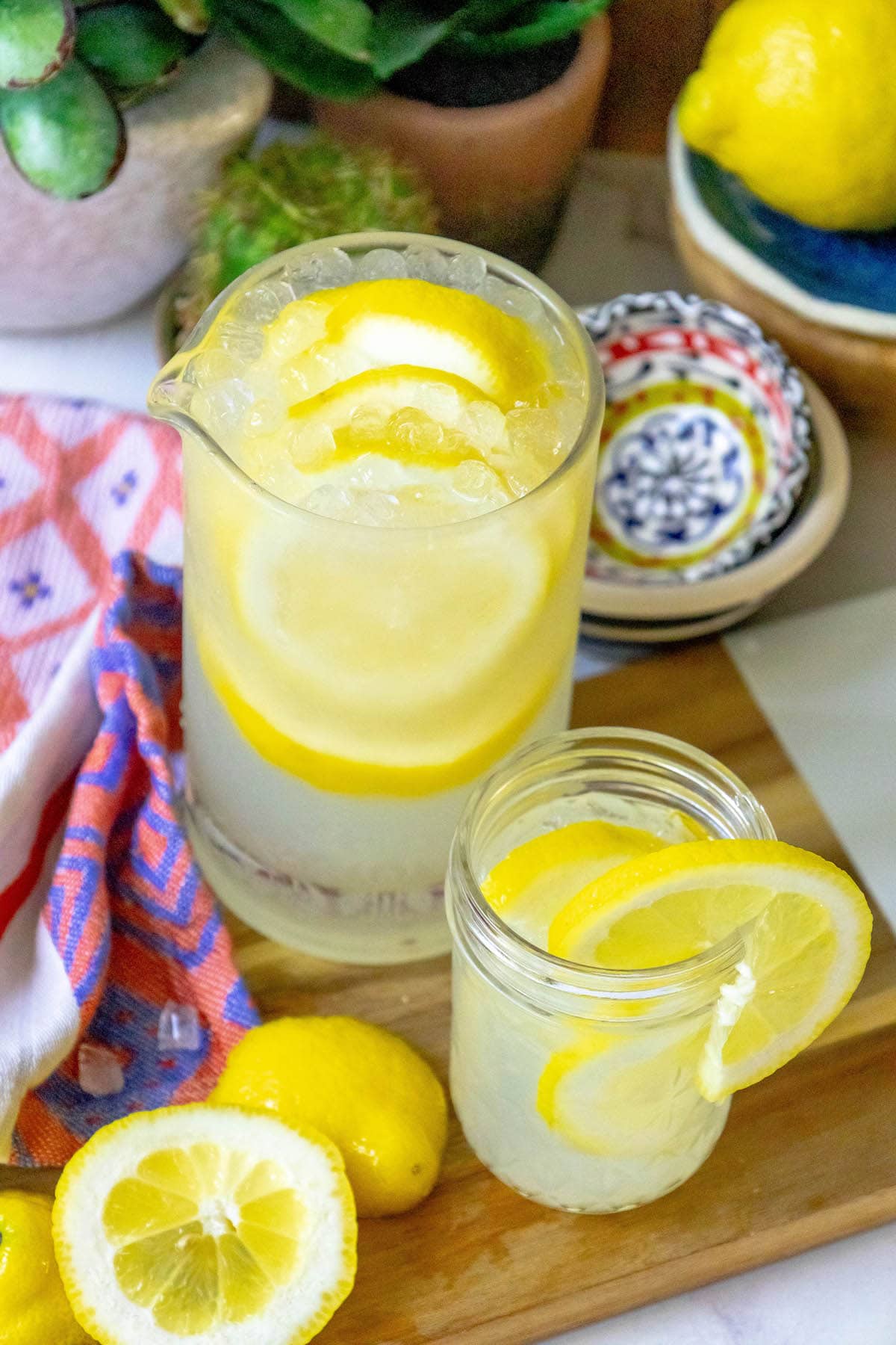 lemonade in a glass jar with a slice of lemon on the side and pebble ice in the glass