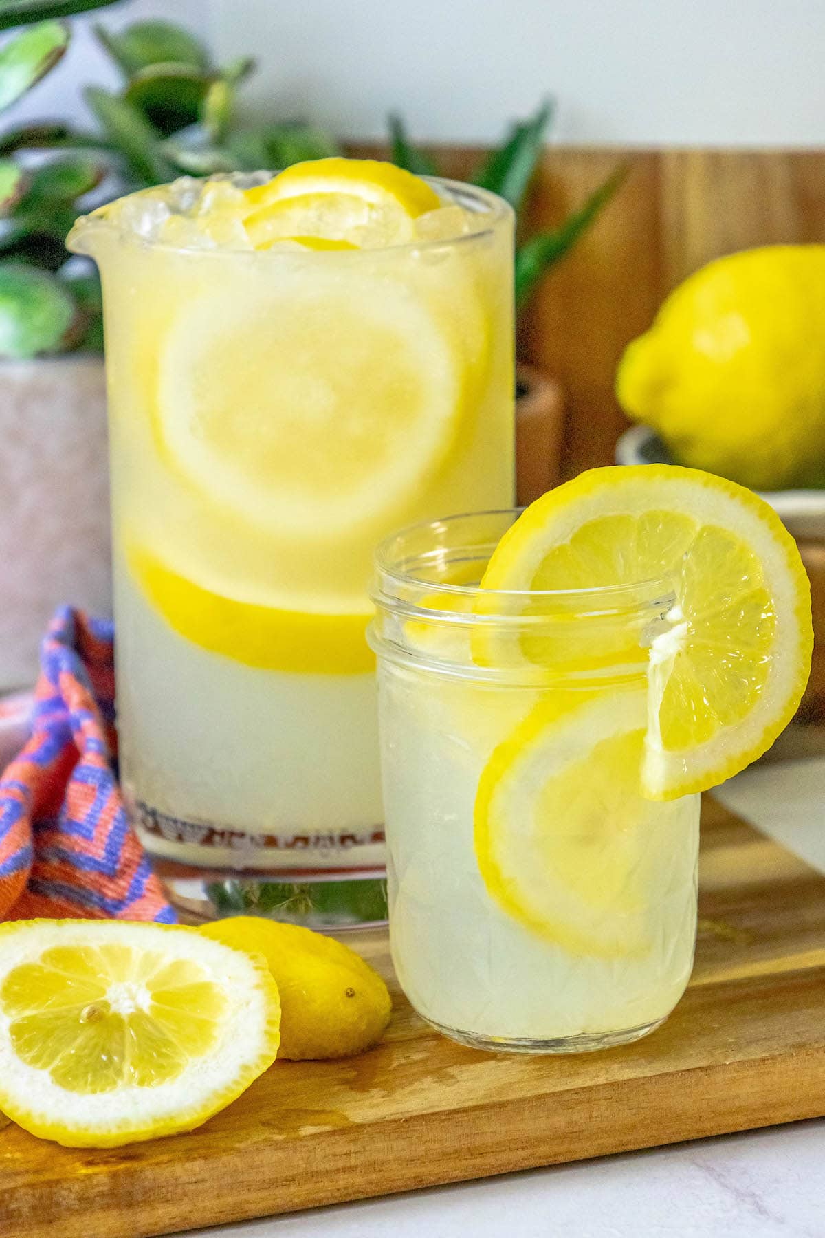 lemonade in a glass jar with a slice of lemon on the side and pebble ice in the glass