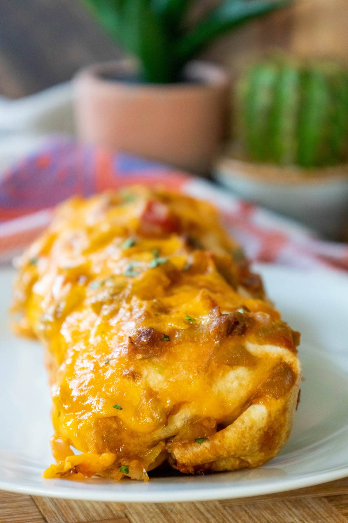 baked breakfast burrito in a red dish smothered in green chile sauce and melted cheese
