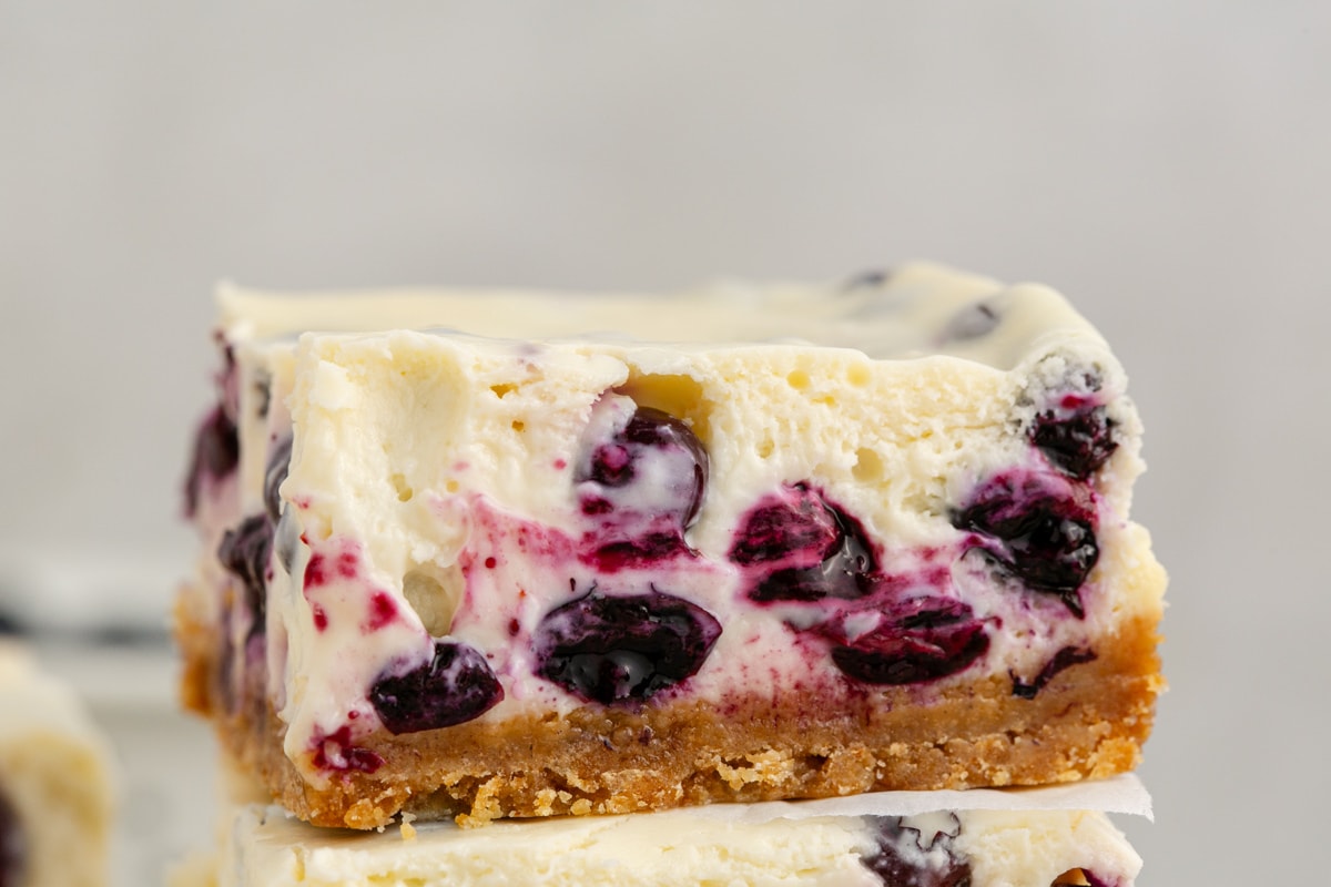 blueberry cheesecake bars stacked on a table