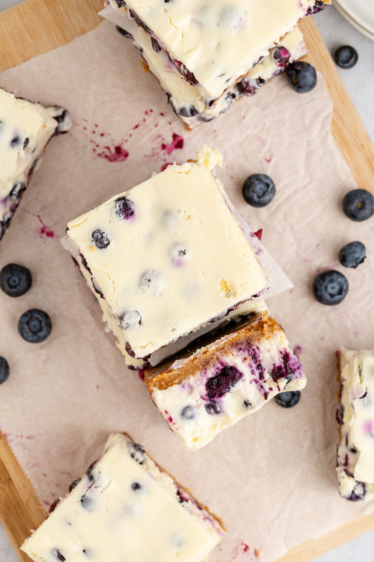 blueberry cheesecake bars sliced on a cutting board
