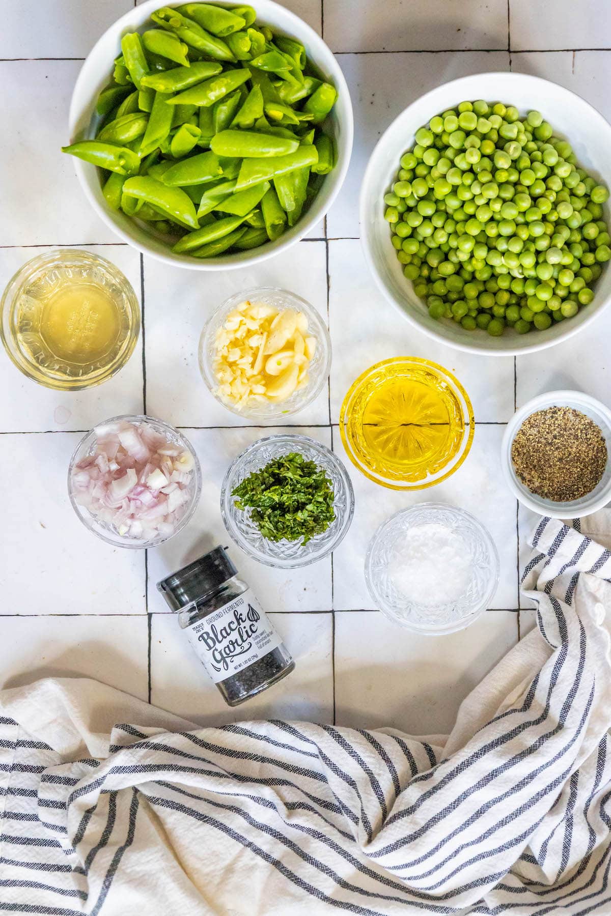 english peas, snap peas, garlic, mint, white wine, diced shallot, herbs, and olive oil on a table