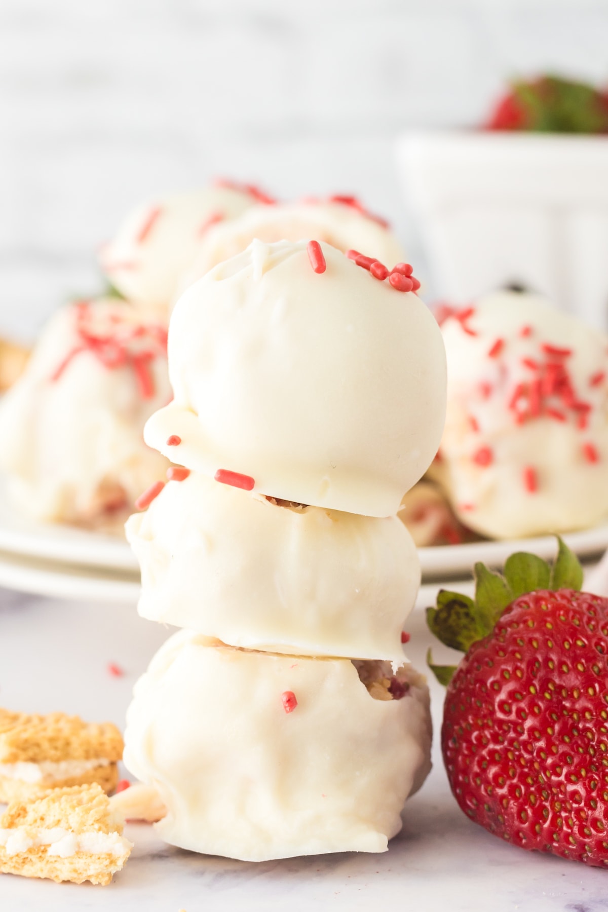 a stack of strawberry shortcake truffles dipped in white chocolate with pink sprinkles on top 