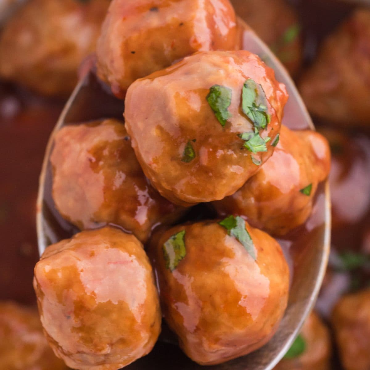 a spoon with meatballs in cranberry sauce